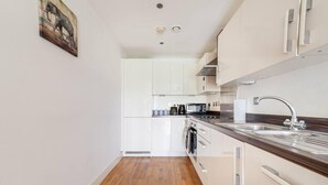 A modern kitchen with white cabinets, a wooden countertop, and a stainless steel sink.