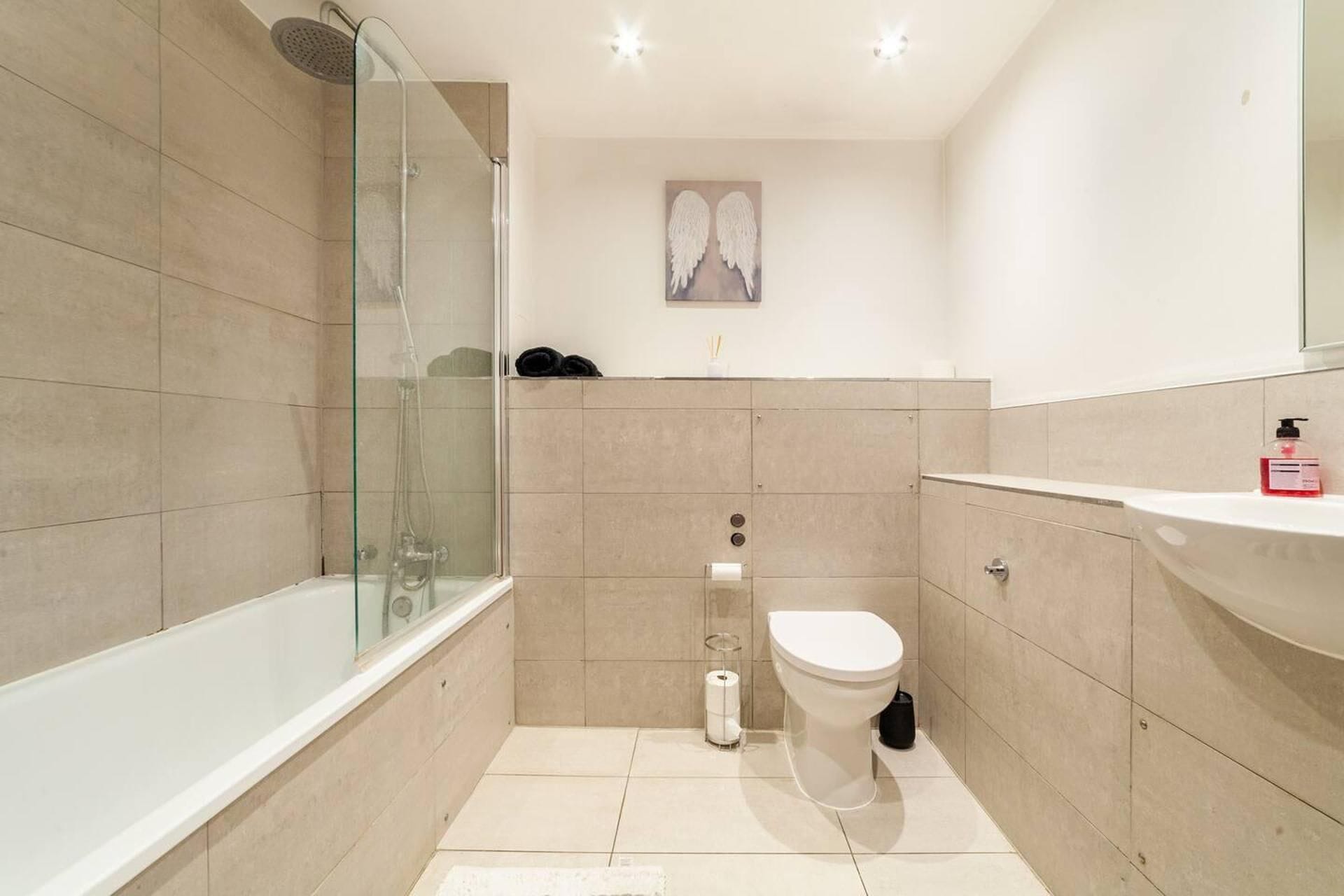 A modern bathroom with a glass shower enclosure, a toilet, and a sink.