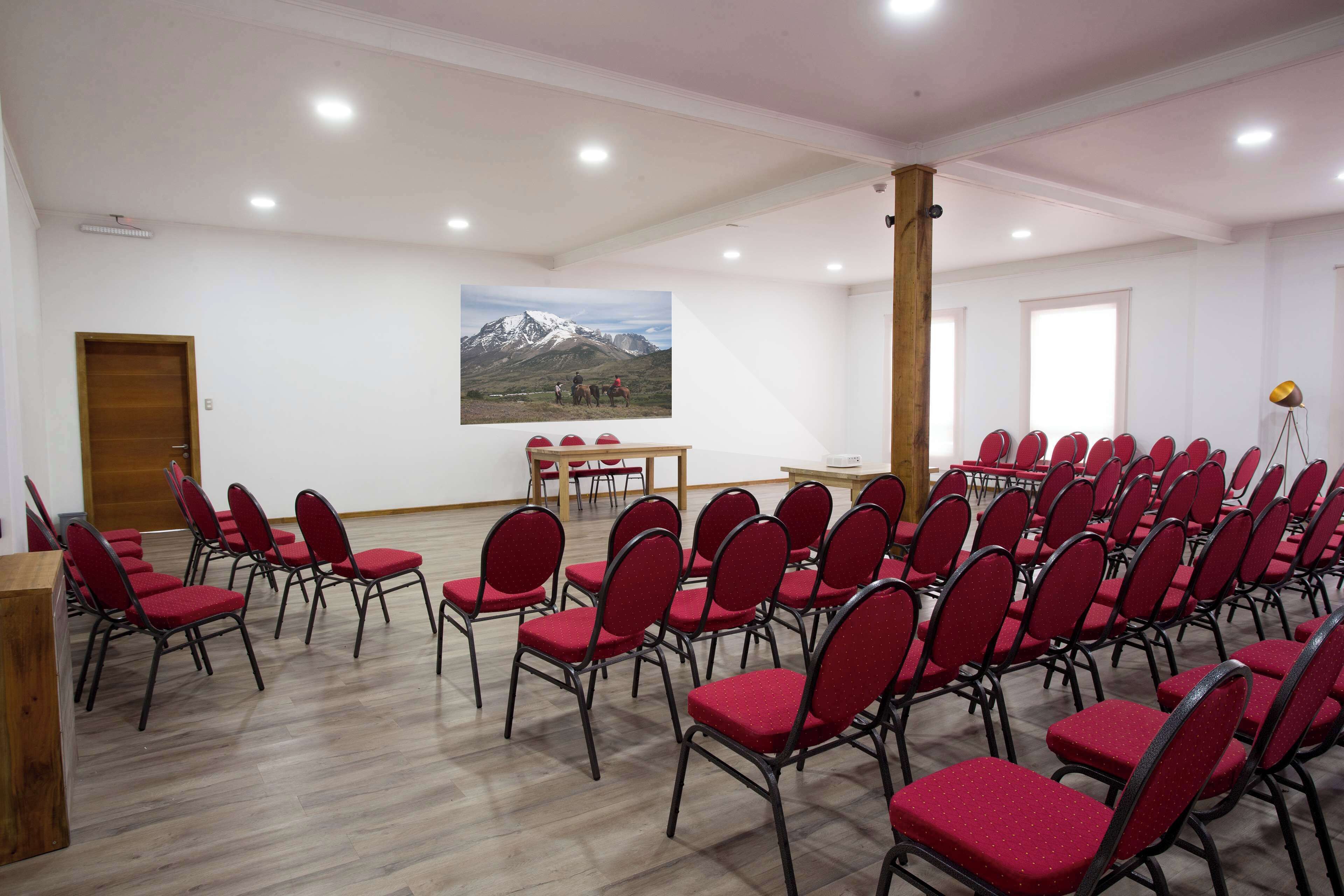 A conference room with rows of red chairs, a wooden podium, and a table with chairs.