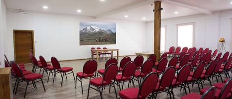 A conference room with rows of red chairs, a wooden podium, and a table with chairs.