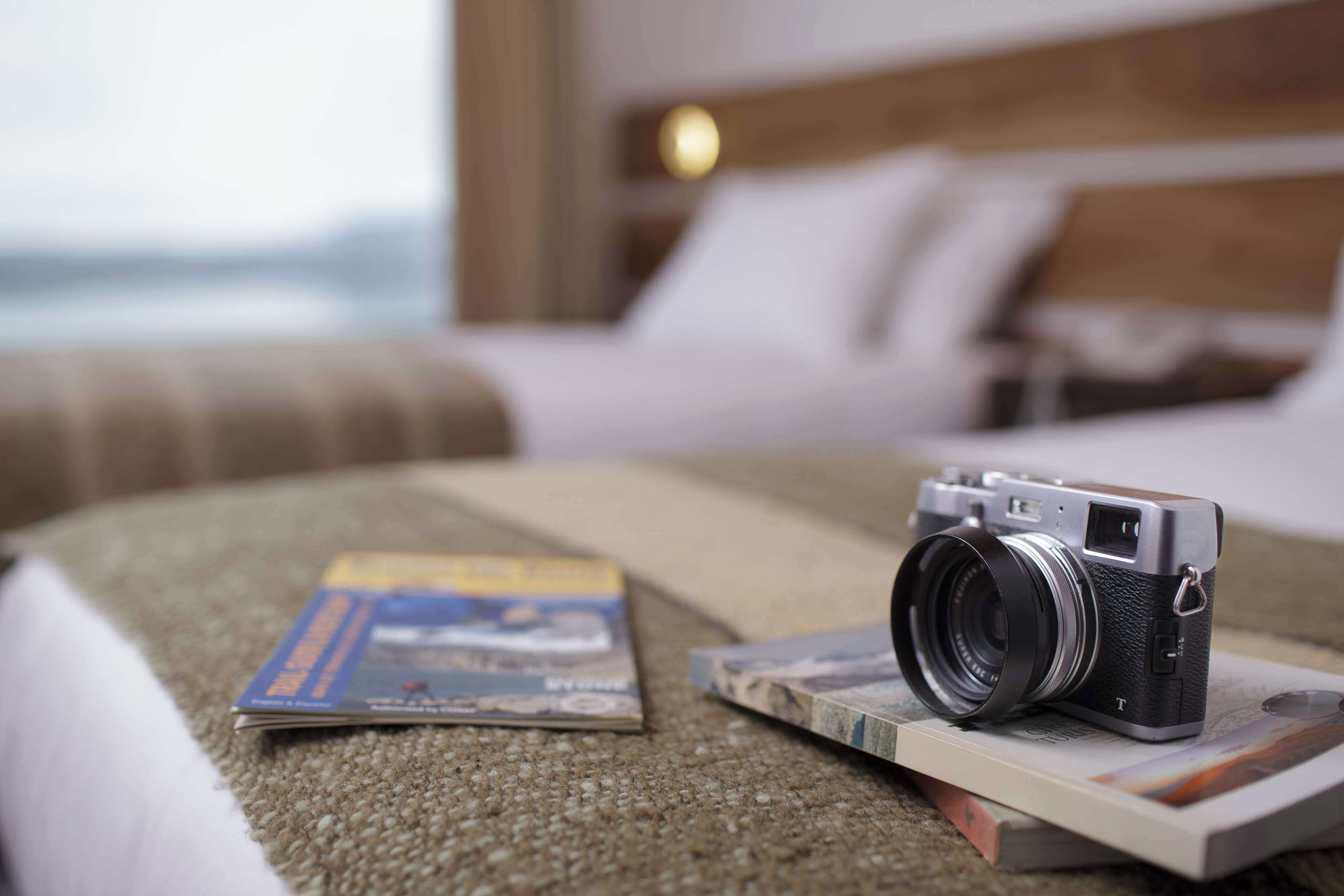 Un appareil photo posé sur un lit, à côté d’un magazine et d’un livre.