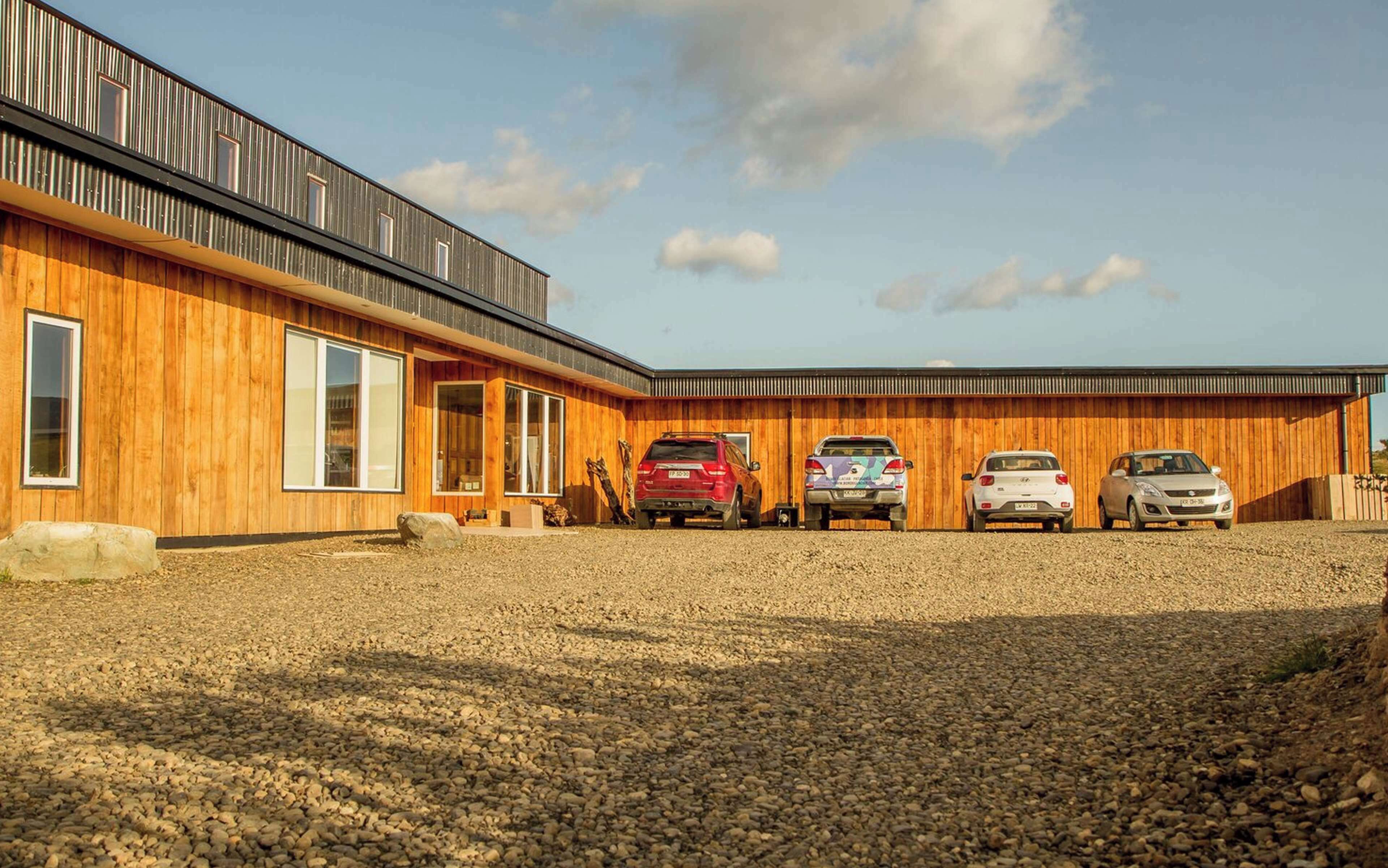 A modern building with a wooden facade and a gravel driveway.