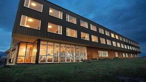 Un edificio moderno con ventanas amplias y techo plano, que presenta un interior espacioso con zonas de estar bien definidas.