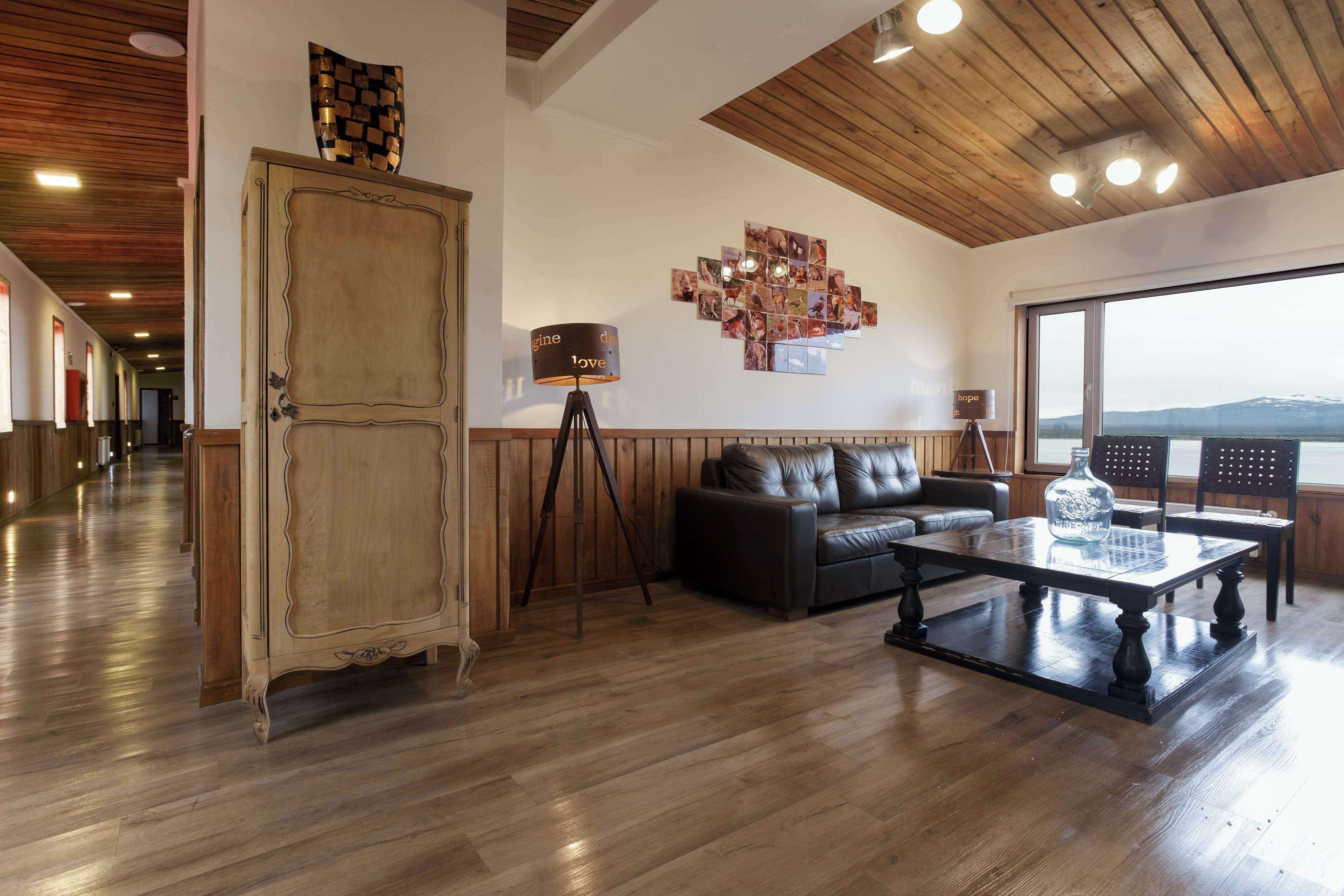 Un salón comedor espacioso con piso de madera, un mueble grande, un sofá de cuero, una mesa de centro y vistas al exterior.