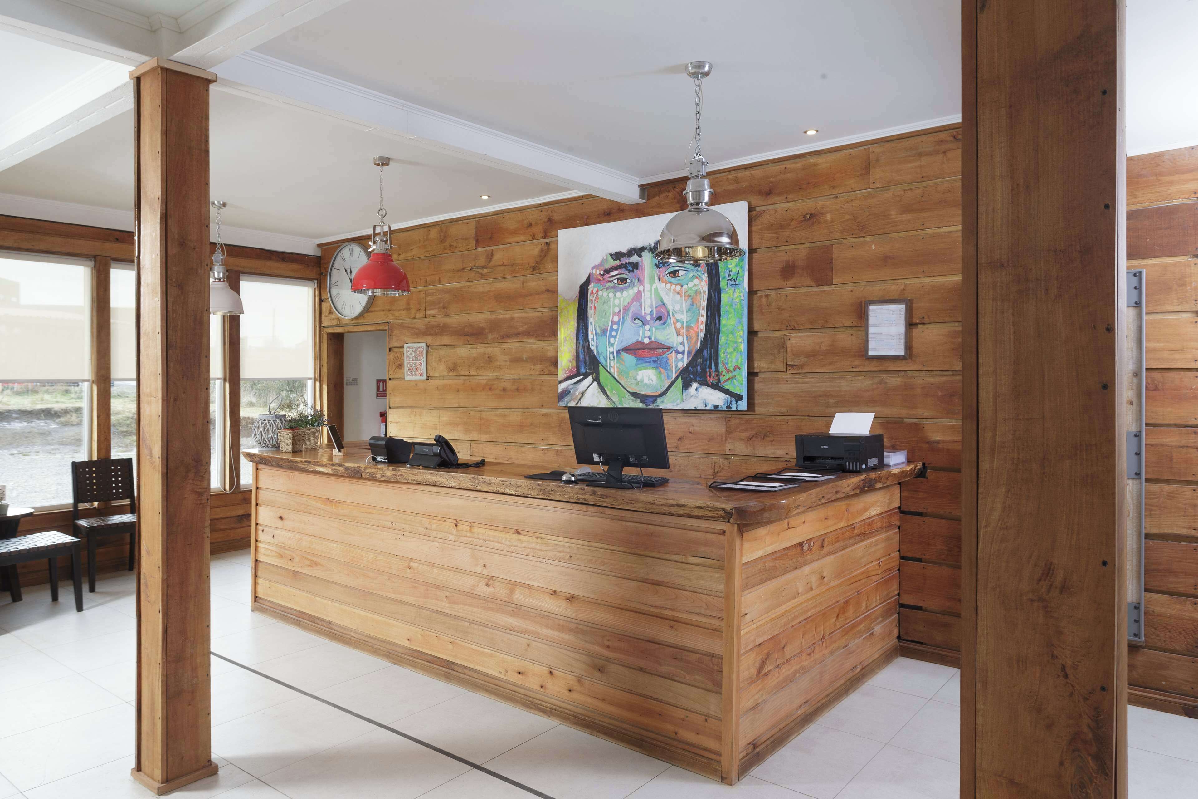 Ein Holzbüro mit Computer, Telefon und einer Uhr.