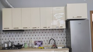Een keuken met witte kasten, een roestvrijstalen koelkast, een gasfornuis en een betegelde achterwand.