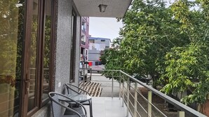 Een overdekt buitengebied met een balustrade, een trap en uitzicht op de straat.