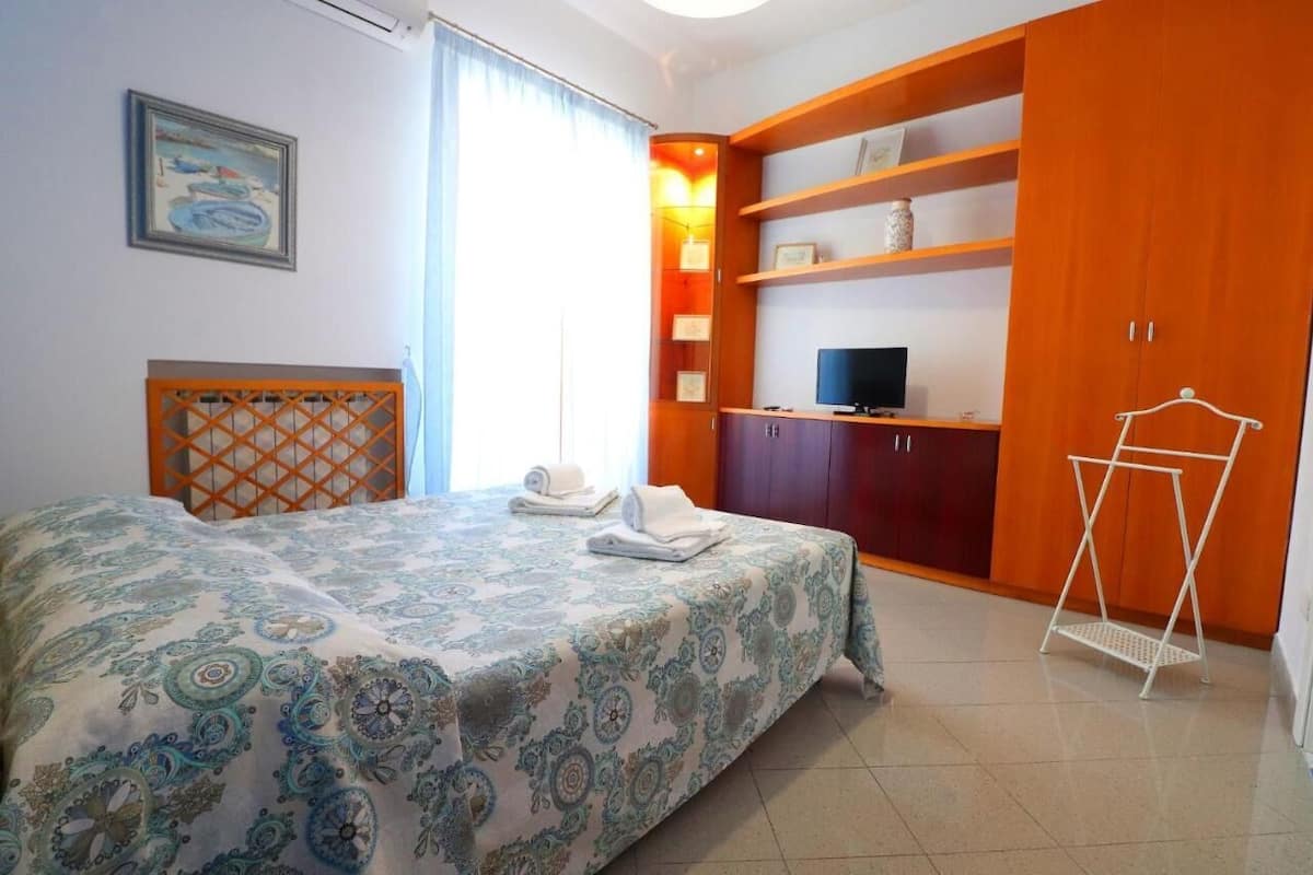 A bedroom with a bed, a TV, a wardrobe, and a shelf unit.