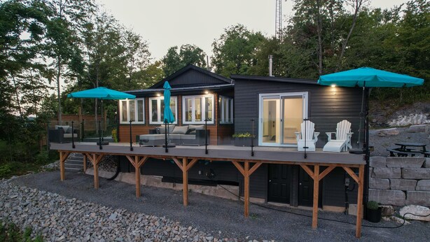 Une cabane moderne dotée d’une terrasse, d’un espace salon extérieur et d’un patio couvert.