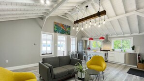 Un vaste espace de vie doté d’un haut plafond, une cuisine équipée d’appareils modernes et un coin repas avec des chaises.
