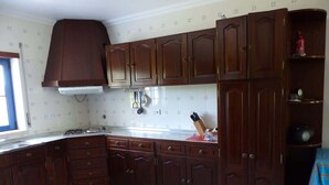 Une cuisine avec des meubles de rangement en bois foncé, une cuisinière et une fenêtre.