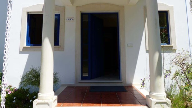 Un bâtiment à la façade blanche, avec une porte bleue et une plaque portant le numéro « 353 ».