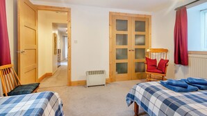 Ein Schlafzimmer mit zwei Betten, einem Holzschrank, einem Heizgerät und einem roten Stuhl.