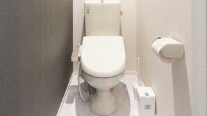 Un baño moderno con inodoro, secamanos y dispensador de toallas de papel.