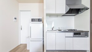Una cocina moderna con microondas integrado, horno y lavavajillas, muebles de cocina blancos y una campana extractora de acero inoxidable.