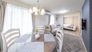 Una habitación moderna con mesa de comedor, sillas, candelabro, sofá, cama y aire acondicionado.
