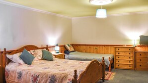 Ein Schlafzimmer mit zwei Einzelbetten, einem Holzkapuzen-Kommode, einem Nachttisch und einer Deckenleuchte.