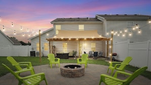 A patio area with a fire pit, outdoor seating, and string lights.
