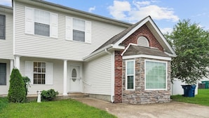 A two-story house with a white exterior, a stone accent wall, and a small front porch.