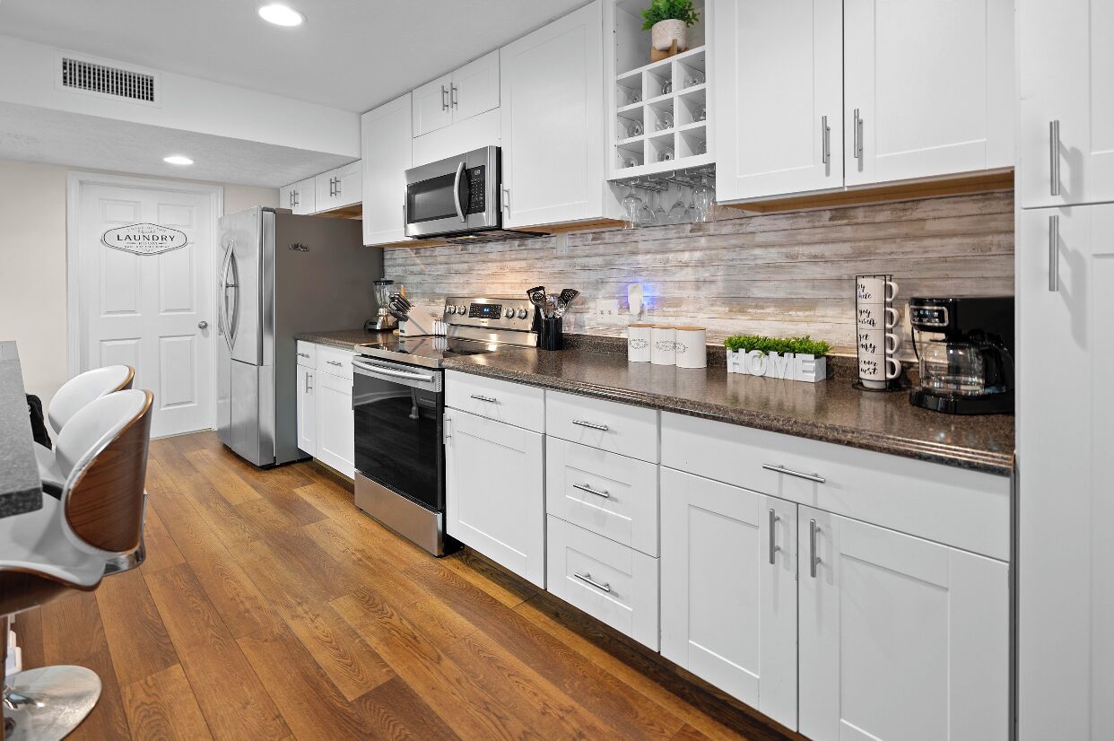 A modern kitchen with white cabinets, stainless steel appliances, and a wooden countertop.