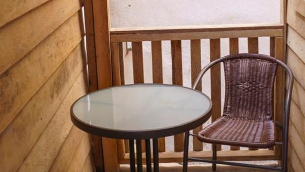 Une terrasse en bois avec une table ronde en verre et deux chaises en osier.