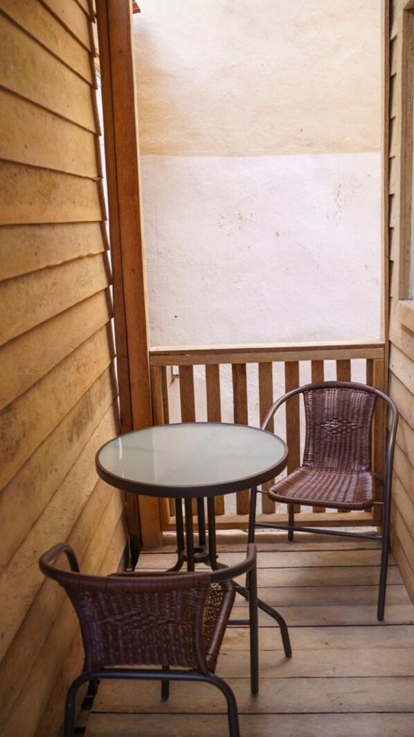 A wooden deck with a round glass table and two wicker chairs. - Cabanas Chac Mool (Isla Holbox)