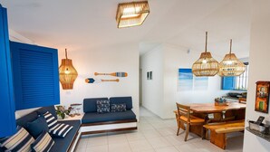 Un salon moderne avec un canapé bleu, une table à manger en bois et des lampes suspendues en osier.