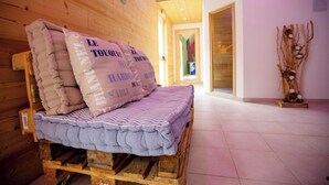 A wooden bed with pillows and a striped blanket in a room with wooden walls and a tiled floor.