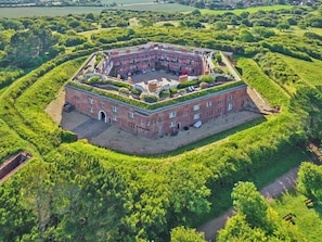 A large, circular brick building with a central courtyard surrounded by lush greenery. - 3 bedroom accommodation in Freshwater (Freshwater)
