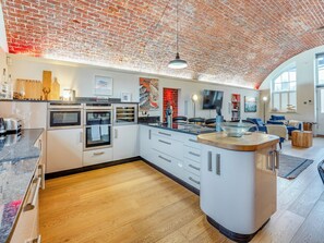 A modern kitchen with a brick ceiling, built-in appliances, and a central island.