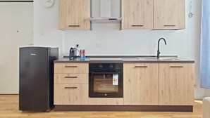 A modern kitchen with wooden cabinets, a black refrigerator, a built-in oven, and a stainless steel sink. - OXILIA (Milan)