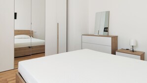 A modern bedroom with a bed, a wooden nightstand, a mirror, and a wardrobe with a sliding door. - OXILIA (Milan)