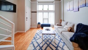 A living room with a sofa, coffee table, and artwork on the wall. - `The Nest`—South End—Rooftop Terrace—Light Rail! (Charlotte)