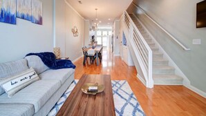 A spacious living room with a sofa, coffee table, and a staircase leading to another level. - `The Nest`—South End—Rooftop Terrace—Light Rail! (Charlotte)
