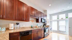 A modern kitchen with dark wooden cabinets, granite countertops, a dishwasher, an oven, and a microwave. - `The Nest`—South End—Rooftop Terrace—Light Rail! (Charlotte)