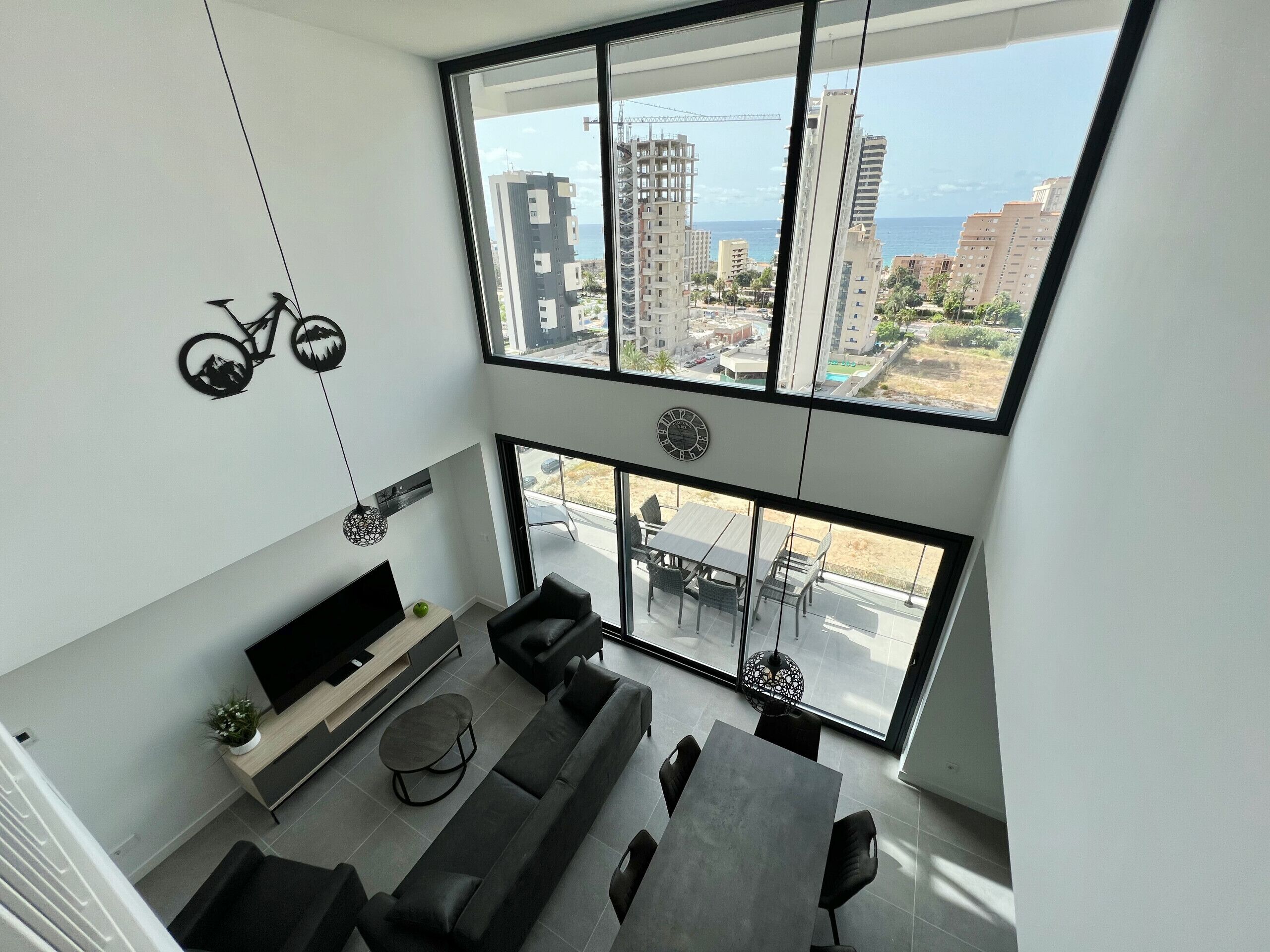 Una sala de estar moderna con un ventanal grande, un sofá, una mesa de comedor y un televisor.