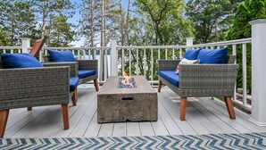 A deck with wicker furniture and a fire pit. - Lake Front Cottage with Amazing Firepit, Private Dock, Sleeps 6 (Chippewa Falls)
