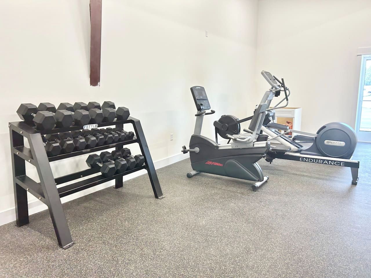 A gym with a rack of dumbbells and an exercise bike.