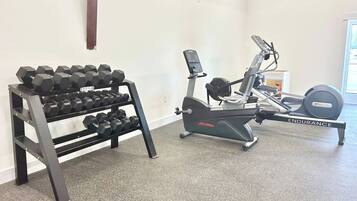 A gym with a rack of dumbbells and an exercise bike.
