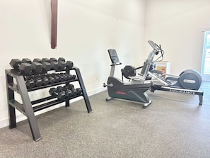 A gym with a rack of dumbbells and an exercise bike.