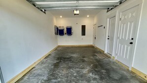 Un couloir étroit avec un sol en béton, des murs blancs et une porte sur le côté droit.