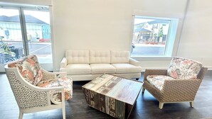 Une pièce avec un canapé blanc, deux fauteuils en osier et une table basse.
