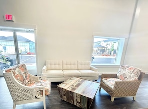 Een kamer met een witte bank, twee rieten fauteuils en een salontafel.