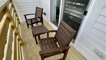 A wooden deck with two wooden chairs and a table.