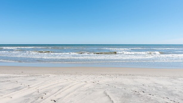 A beach with clear skies and calm waves. - Enjoy The Ocean Breeze just Steps from the Beach! (Corolla)