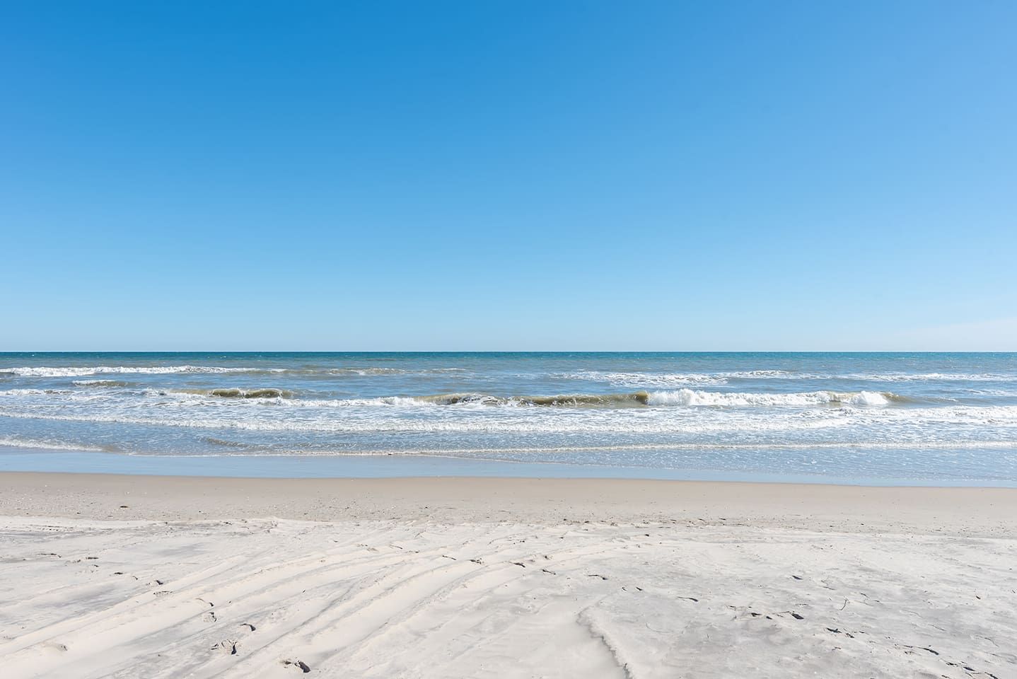 A beach with waves and a clear sky.