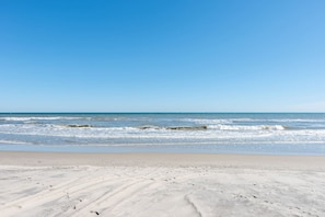 A beach with waves and a clear sky.