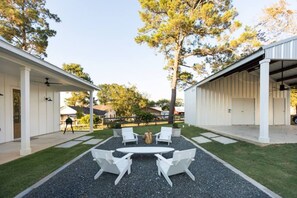 A covered outdoor seating area with a table and chairs, surrounded by a gravel path and grass. - NEW urban cottage, The Vine & Round Top! (Austin County)