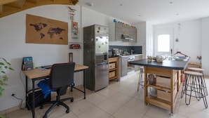 Una cocina moderna con una isla central, un refrigerador empotrado y una zona de comedor con taburetes.