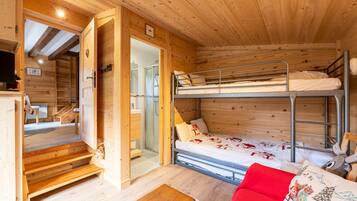 L’intérieur d’une cabane en bois, avec un lit superposé, une petite table et un canapé rouge.